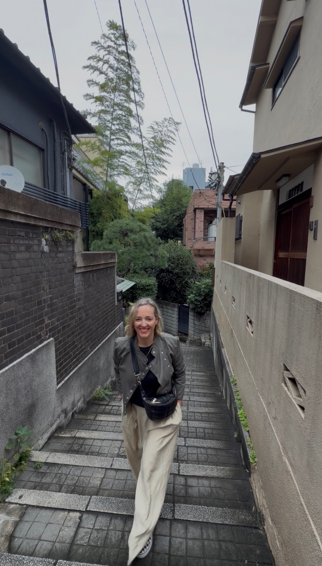 Nadine walking up a stone stair in a quiet Japanese neighbourhood